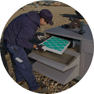 A man in blue jacket and hat working on an air filter.