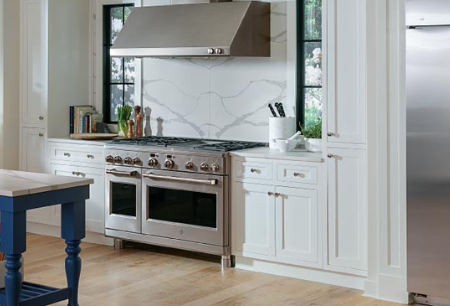 A kitchen with white cabinets and wood floors.