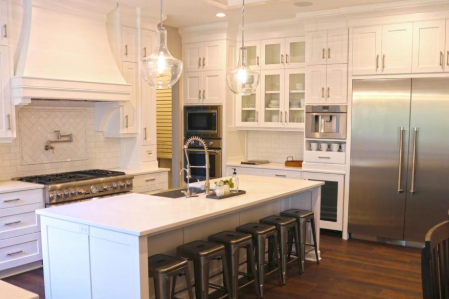 A kitchen with white cabinets and wooden floors.