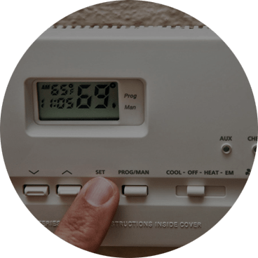 A person is touching the temperature on an electronic thermostat.