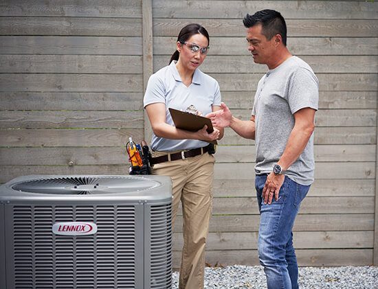 A man and woman standing next to an air conditioner.